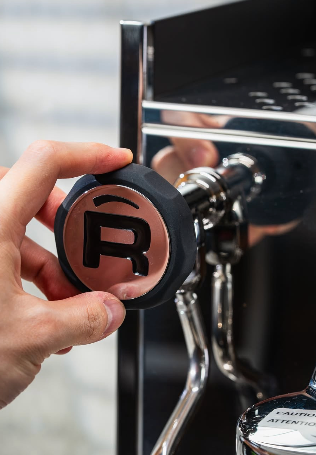 knop van rocket espressomachine die wordt aangeraakt door een hand